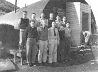 A group of 11 men standing by a Quonset (Pacific?) Hut. [ Robert Arnts]