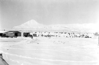 Umnak Air Base taken from outside our Dispensary. The freight doc on the left side. A man is walking on the runway.  [Don Blumenthal]