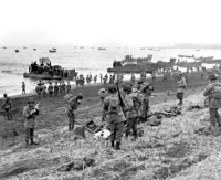 Southern landing force disembarking at Attu's Massacre Bay; landing boats pour scores of soldiers onto a sandy beach. 11 May 1943. [George & Nadine Smith]