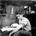 On Attu, my home for several years, taken inside the hut. Looks as if I'm writing home or to some girl! [Al Gloeckler]